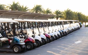 Many golf carts for golf player on a golf course. golf course carts cars at luxury resort sport venue in neat line row.